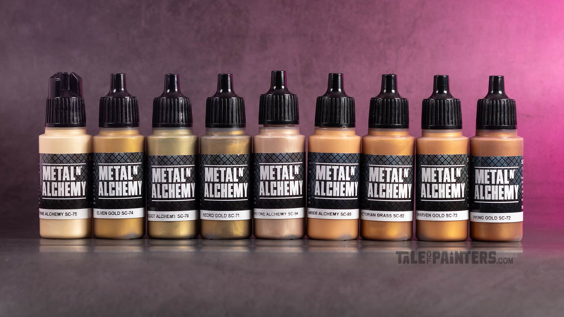 9 bottles of various gold paints from Scale 75's Metal'n'Alchemy range lined up on a concrete background with pink light