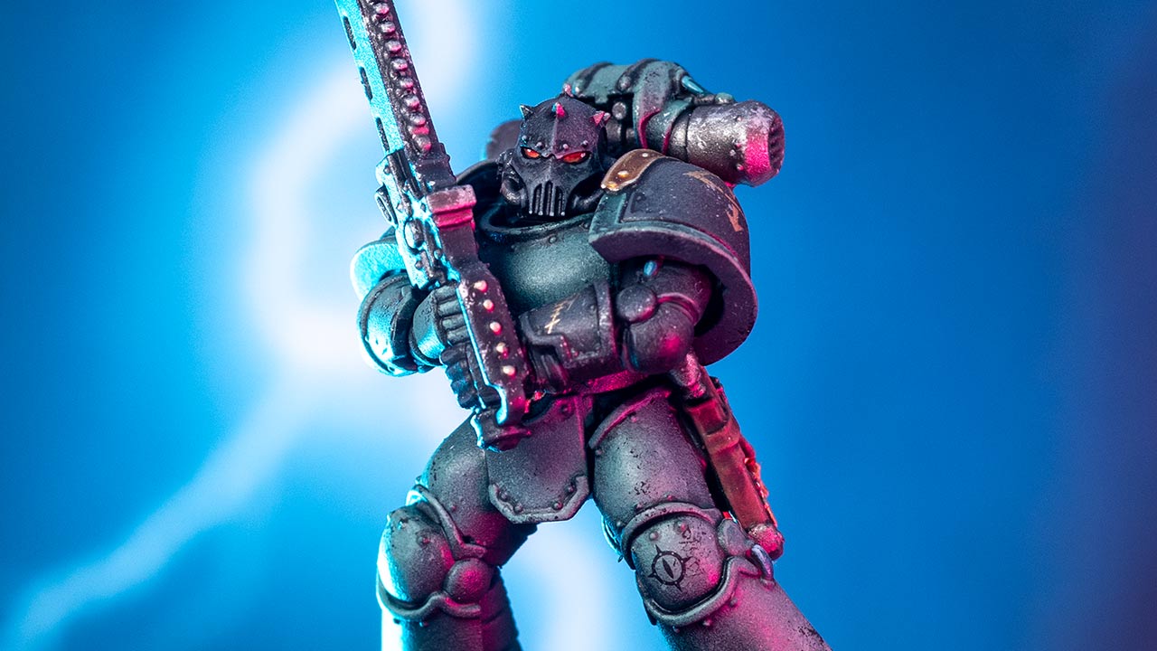 A Sons of Horus Despoiler in MkIII armour swinging a chainsword in front of a dramatic blue sky with lighting