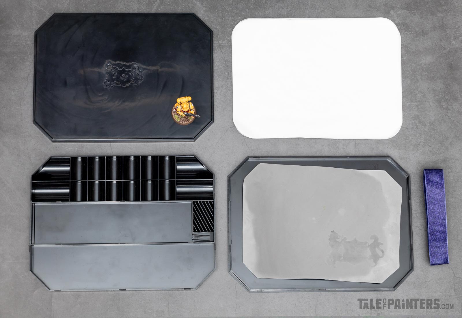 All components of Chronicle's black wet palette laid out on a concrete background, with a Primaris Space Marine for size comparison, shot for a review