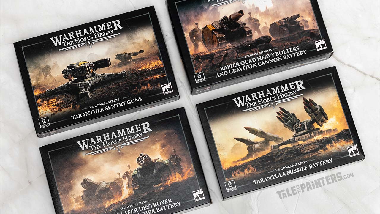 Four Horus Heresy model set boxes arranged on a white marble background, featuring Tarantula Sentry Guns and Missile Battery, and Rapier Quad Heavy Bolter and Graviton Cannon plus Laser Destroyer and Quad Launcher batteries. Photographed for review purposes.