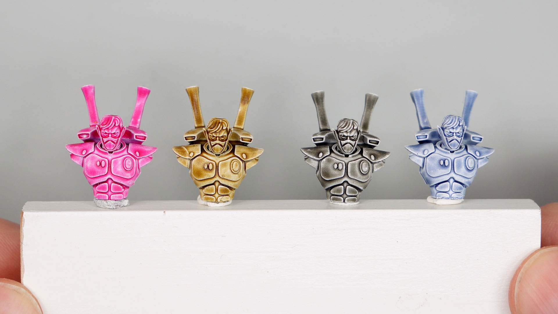 Four white primed Aeldari busts painted with Magenta Wash, Petroleum Brown Wash, Brown Grey Wash, and Payne's Grey Wash from the AMP Colors range