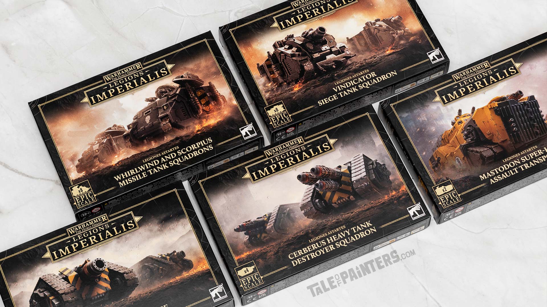Legions Imperialis Mastodon, Cerberus, Typhon, Vindicator, and Whirlwind/Scorpius tanks boxes arranged on a white marble background, photographed for review purposes