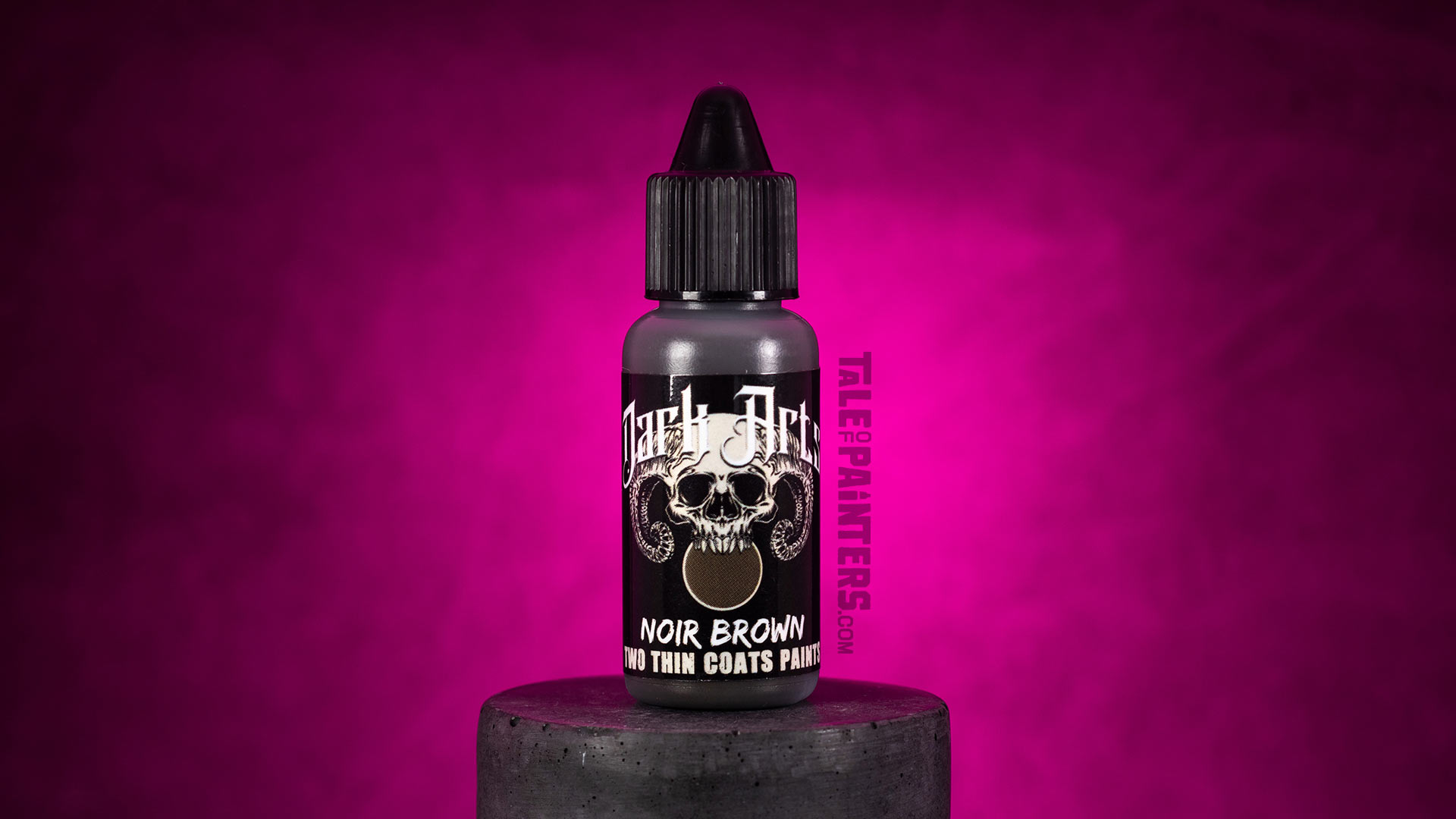 Noir Brown paint bottle from the Two Thin Coats Dark Arts range, on a concrete plinth, background lit with pink light