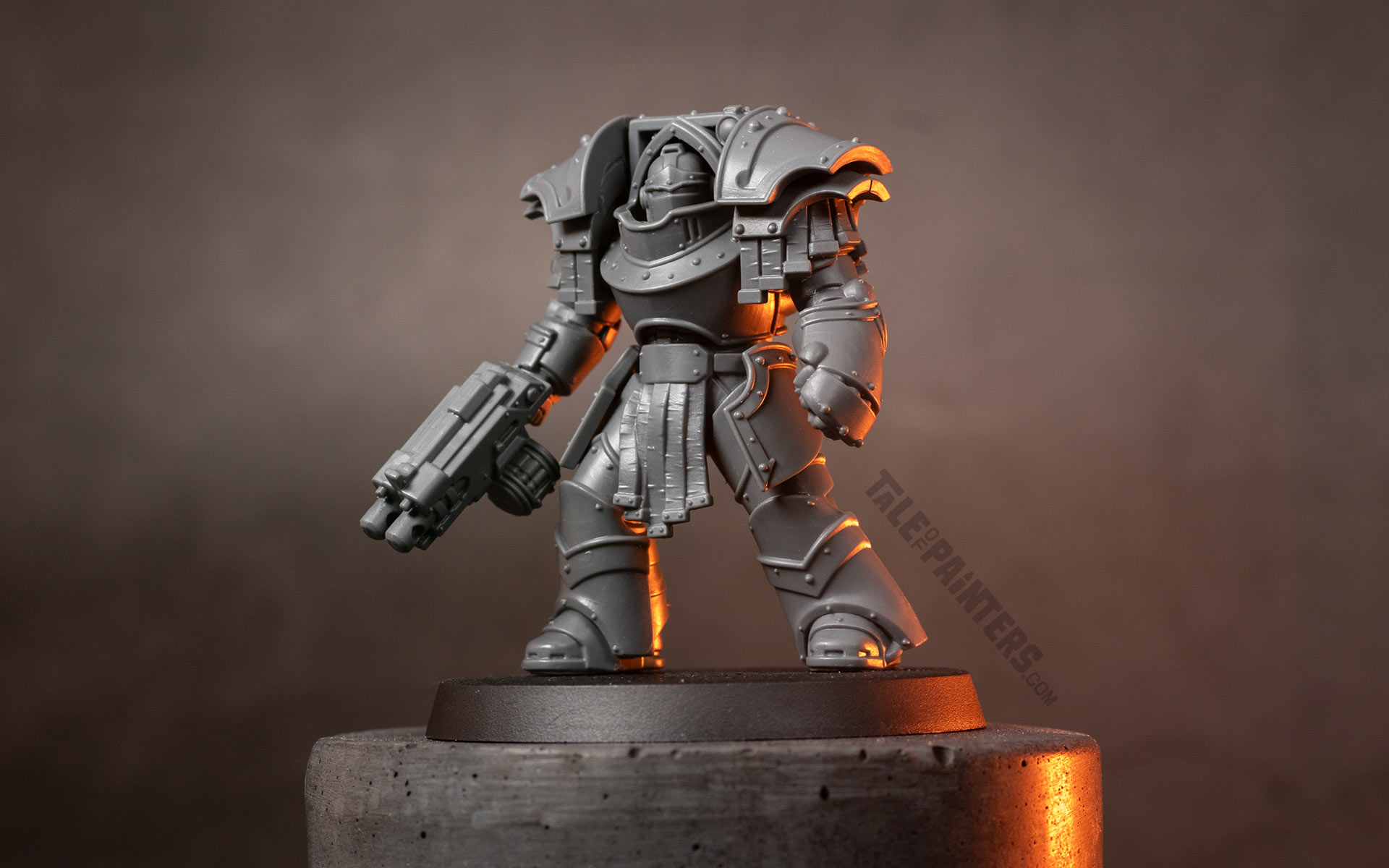An unpainted new Cataphractii Terminator model with power fist and combi-bolter, on a concrete plinth, dramatically lit with orange light