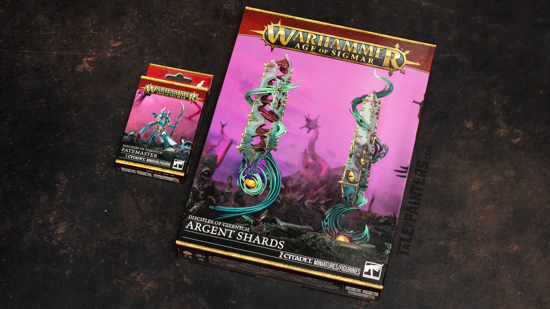 Disciples of Tzeentch Fatemaster and Argent Shards model kit boxes arranged on a dark brown background for review purposes