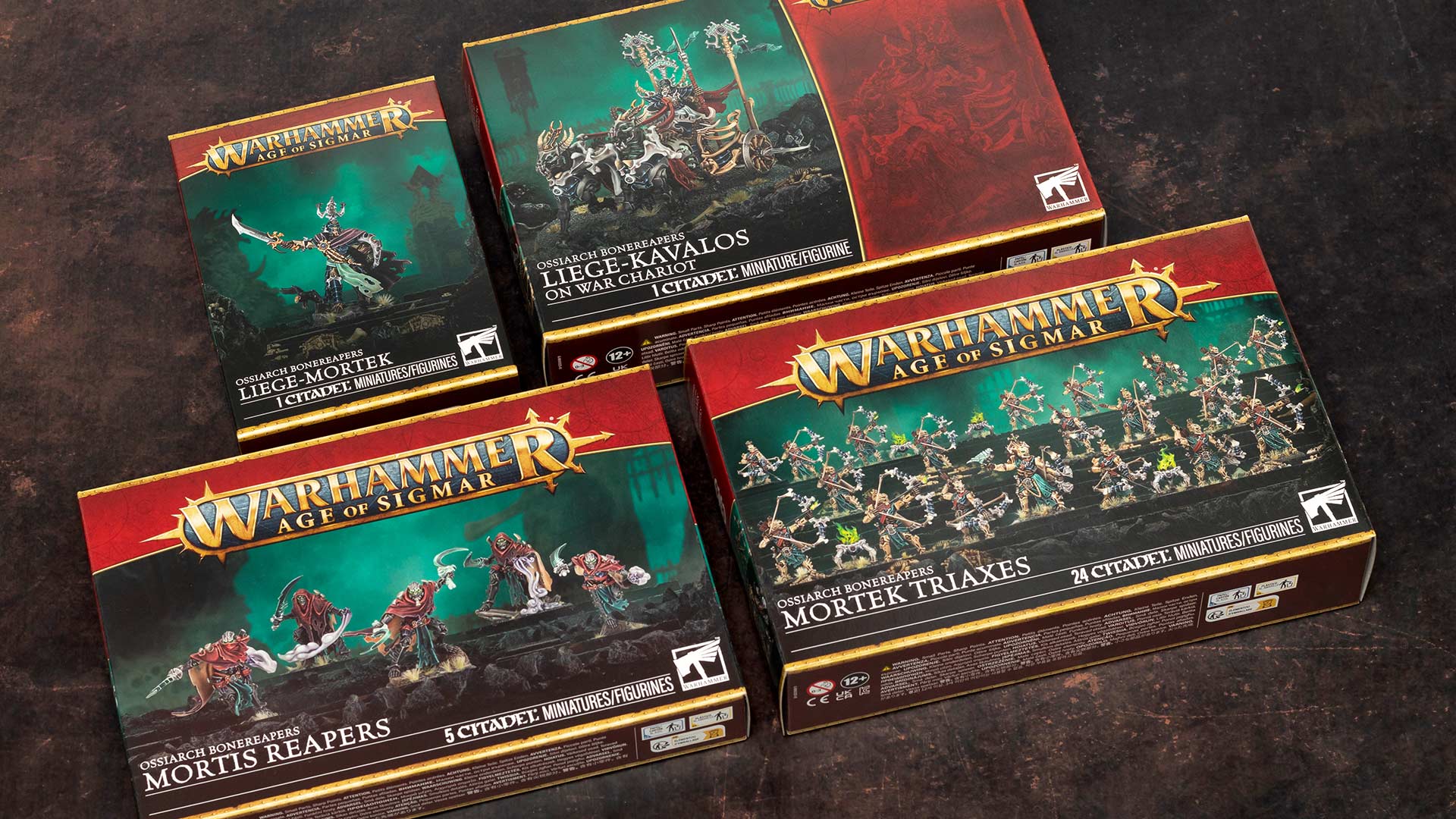 Age of Sigmar Ossiarch Bonereapers model kit boxes (Liege-Mortek, Liege-Kavalos on War Chariot, Mortis Reapers, and Mortek Triaxes arranged on a dark brown background, photographed for a review and unboxing
